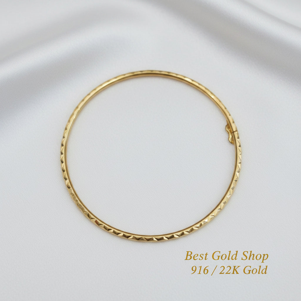 Detailed view of geometric diamond-cut facets on the gold bangle