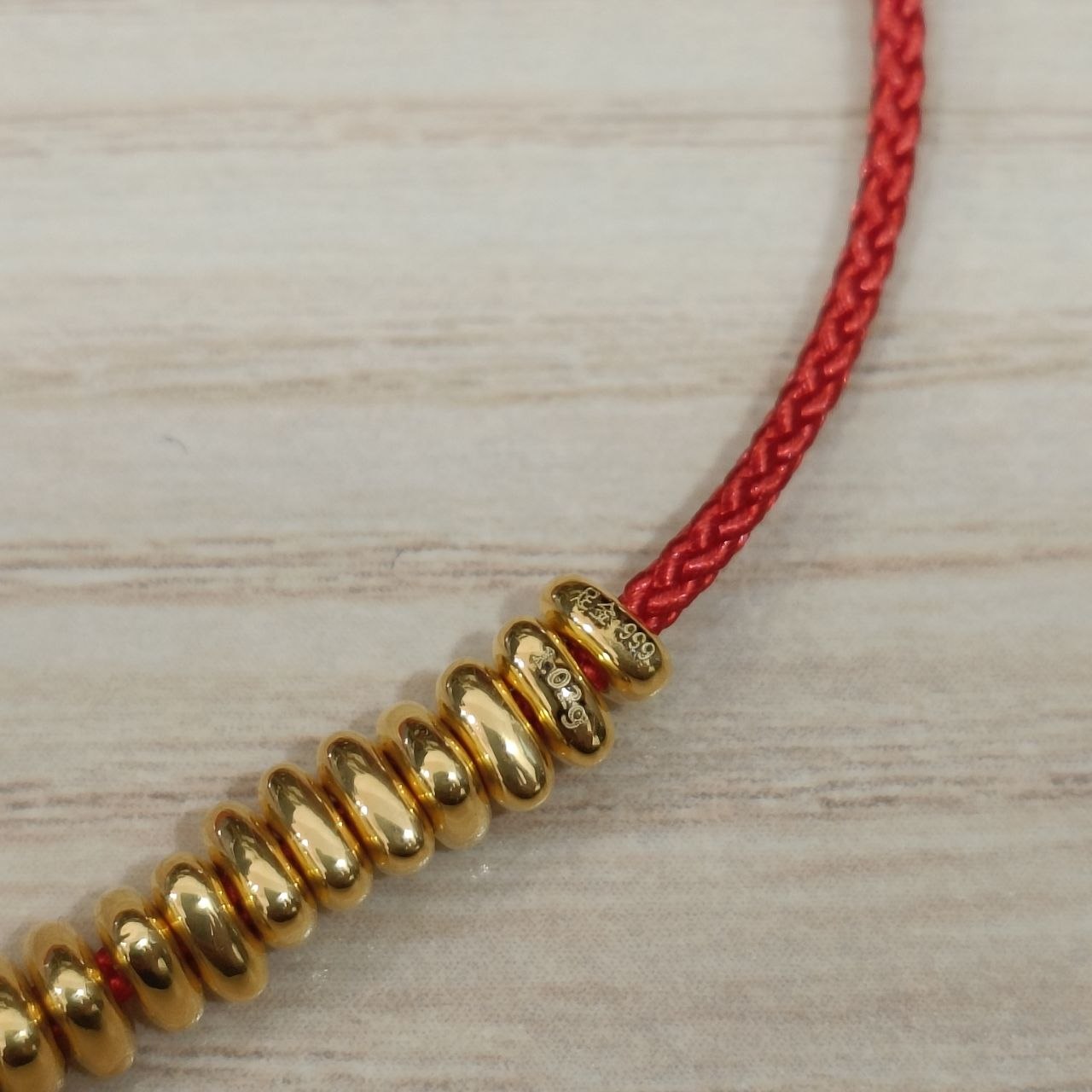 999 gold hallmark detail on bead strand red cord bracelet
