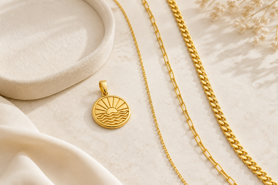 Yellow-gold pendant displayed beside three gold chain styles on a cream surface