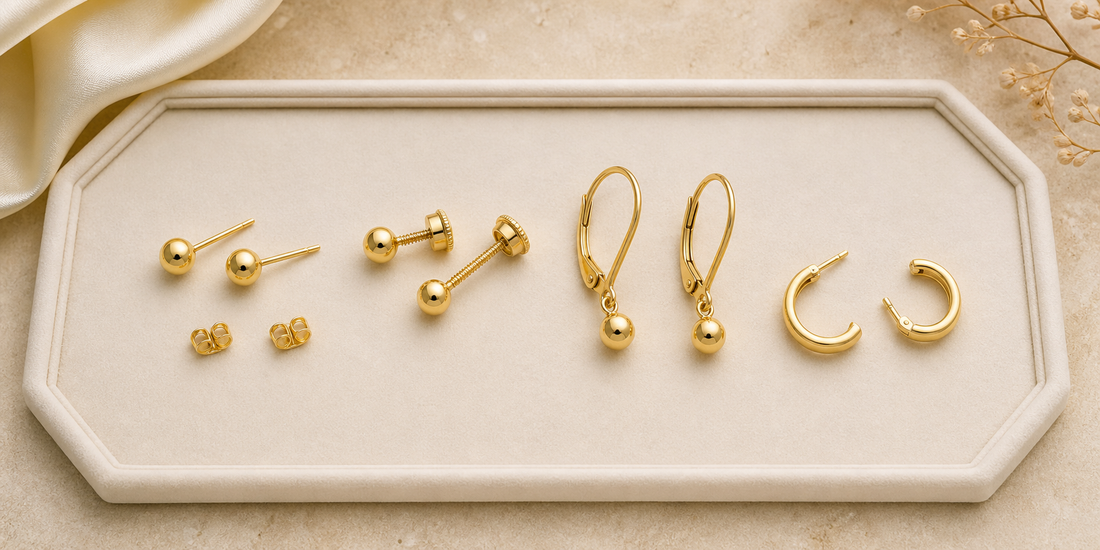 Gold stud, screw-back, lever-back and hinged hoop earrings on an ivory tray