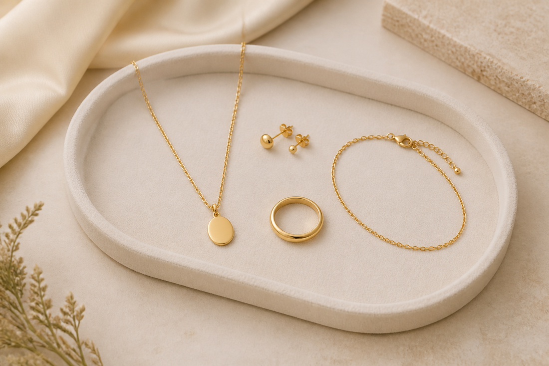Curated gold jewellery capsule collection with necklace, stud earrings, ring and bracelet on an ivory tray