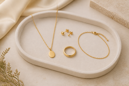 Curated gold jewellery capsule collection with necklace, stud earrings, ring and bracelet on an ivory tray