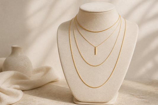 Four gold necklaces at different lengths displayed on an ivory jewellery bust