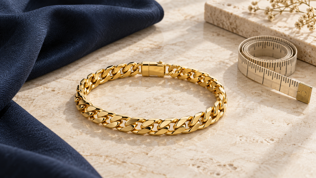 Yellow-gold link bracelet with clasp beside a measuring tape and navy fabric on an ivory surface.