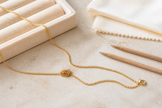 Knotted fine gold chain beside wooden jewellery picks and soft cloth