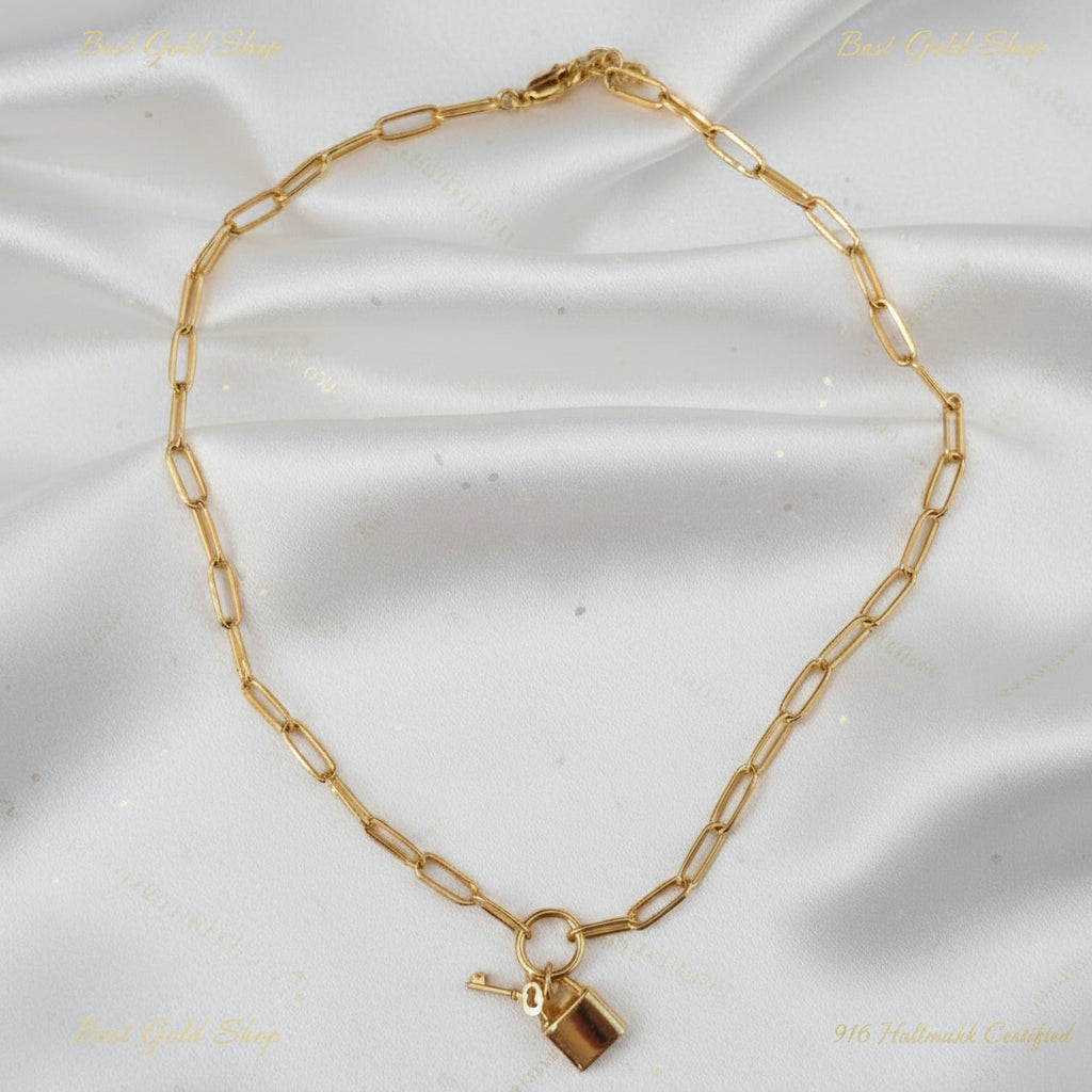 Detailed view of polished 22K Gold paperclip links with lock and key charms.
