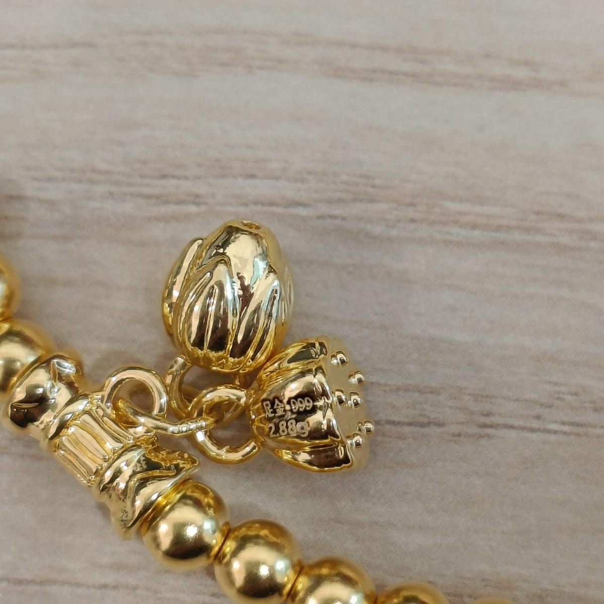 999 gold hallmark and lotus charm detail on bead bracelet