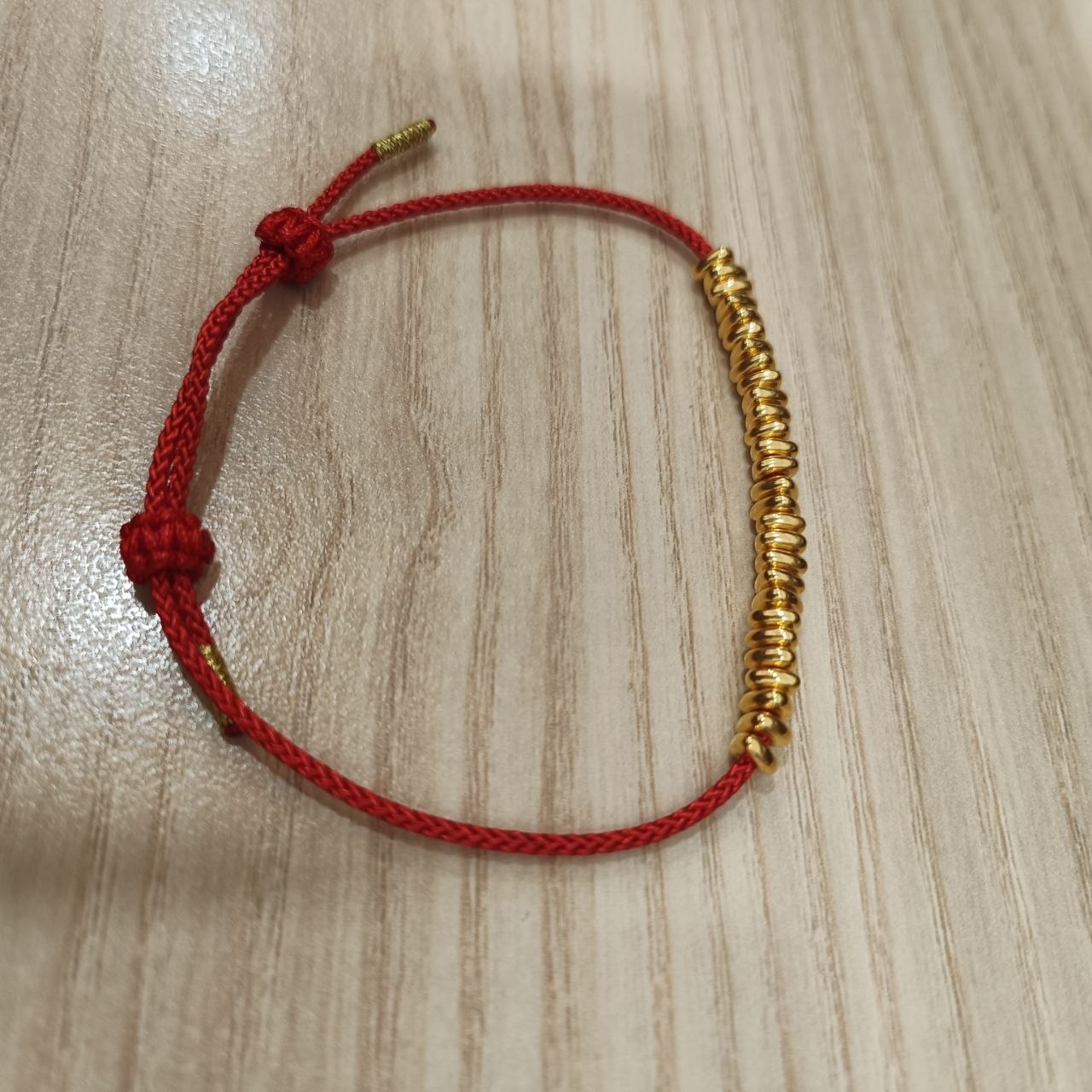 999 gold bead strand bracelet showing sliding knot - side view