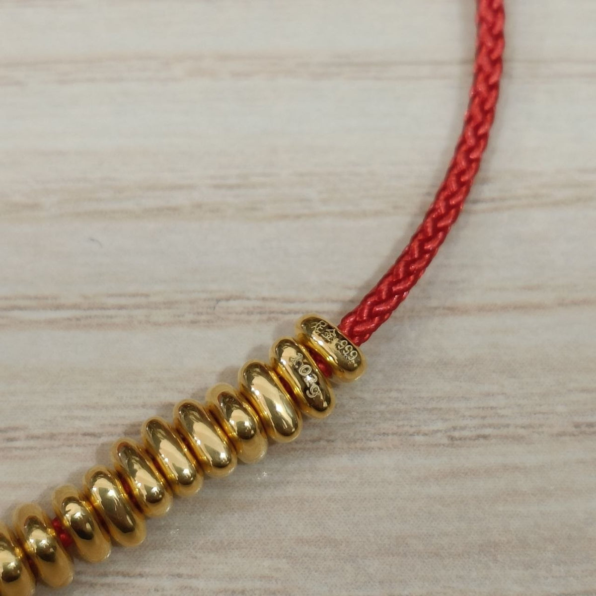 999 gold hallmark detail on bead strand red cord bracelet